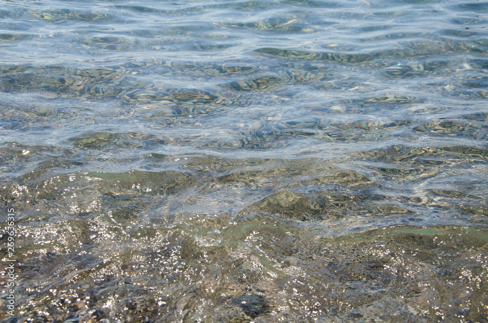 Abstract sea background, view on ripple surface of water, stone bottom underwater