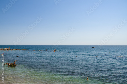 Colorful seascape, people swimming at sea shore