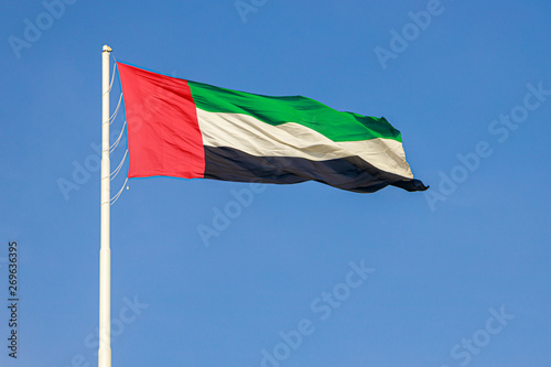 Flag of United Arab Emirates flying in the wind against a blue sky