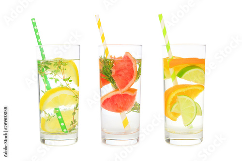 Variety of citrus infused detox water drinks in glasses with paper straws isolated on a white background