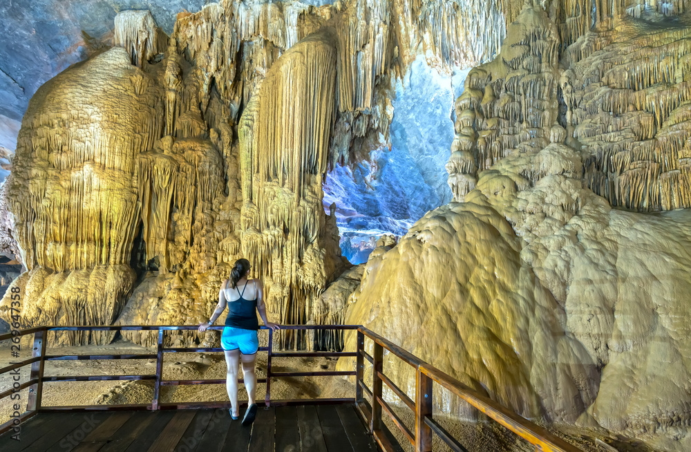 Ninh Binh, Vietnam - April 7th, 2019: Back view silhouette traveler woman watching Paradise Cave with stalactites and stalagmites in Phong Nha national park, Quang Binh, Vietnam
