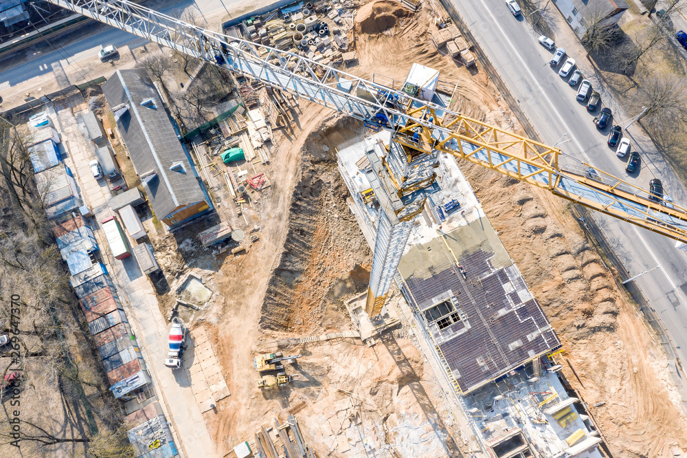 construction of new residential area. yellow tower crane standing high near building in progress. aerial view