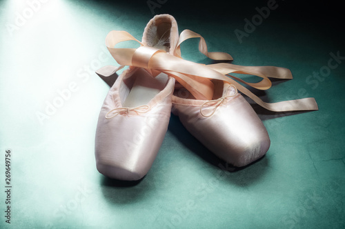 Pointe shoes ballet dance shoes with a bow of ribbons beautifully folded on a green background.