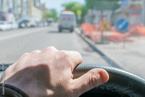 View of the driver s hand on the steering wheel on the background of road repair signs