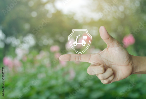 Motorcycle with shield flat icon on finger over blur pink flower and tree in park, Business motorbike insurance concept