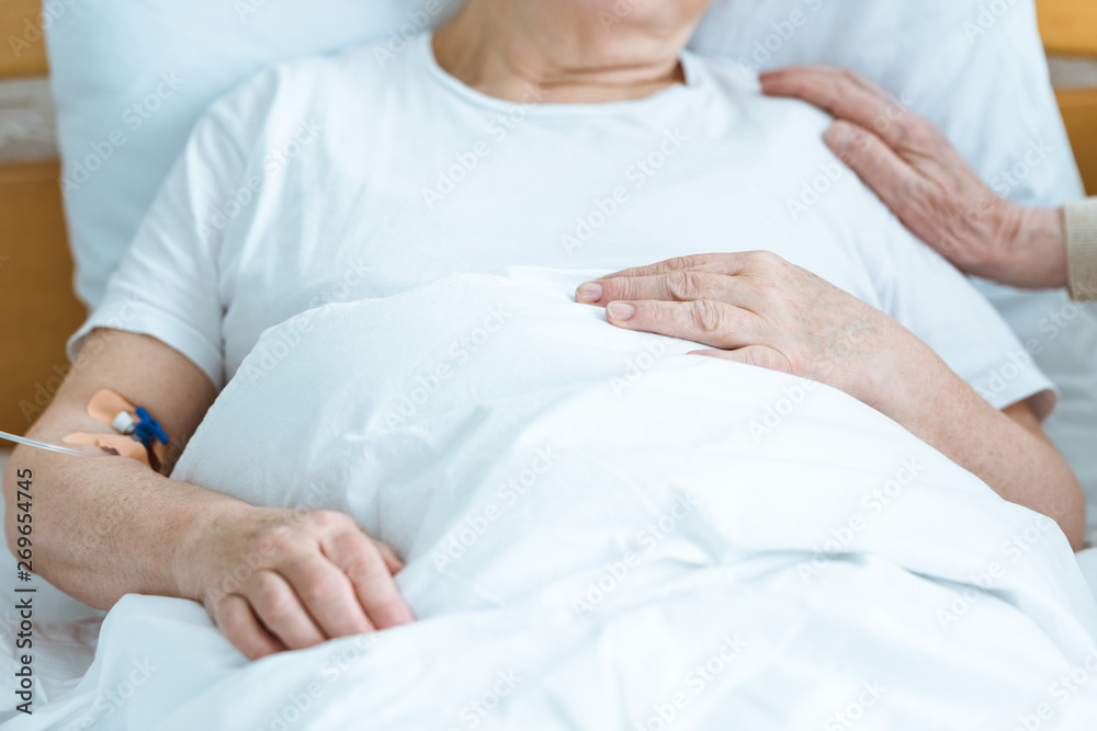 partial view of sick senior woman with husband in hospital partial view of sick senior woman with husband in hospital