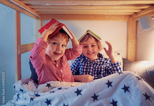 Konstfotografi cheerful kids, brothers having fun, playing with books on the bunk bed during be