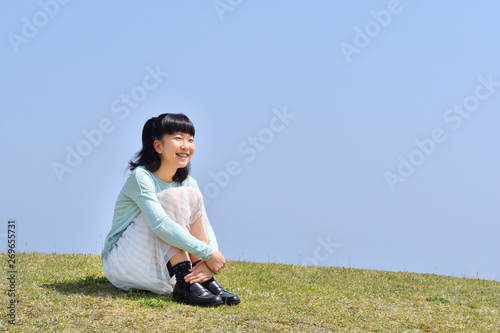 芝生広場に座る女の子（青空）