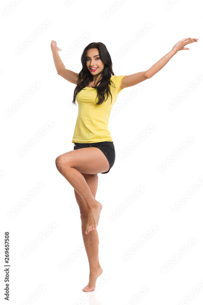 Happy Young Woman Is Standing Barefoot On One Leg With Arms Outstretched Happy Young Woman Is Standing Barefoot On One Leg With Arms Outstretched