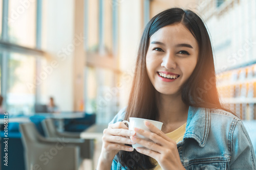 Asian woman in a cafe drinking coffee .Portrait of Asian woman smiling in coffee shop cafe vintage color tone.