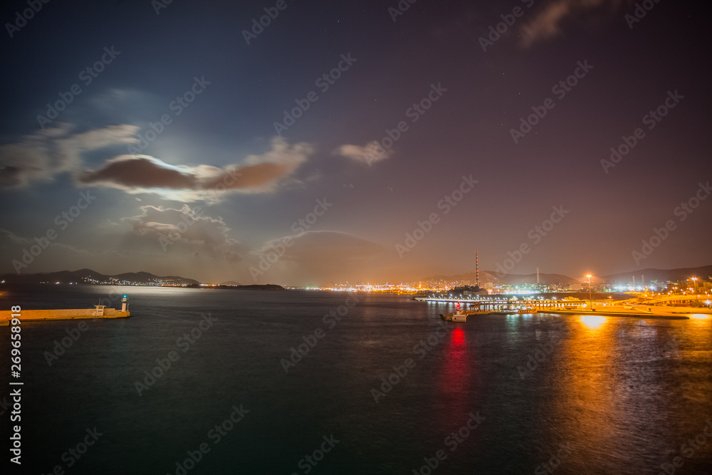 Night view of Athens Piraeus harbor with moon hidden by clouds