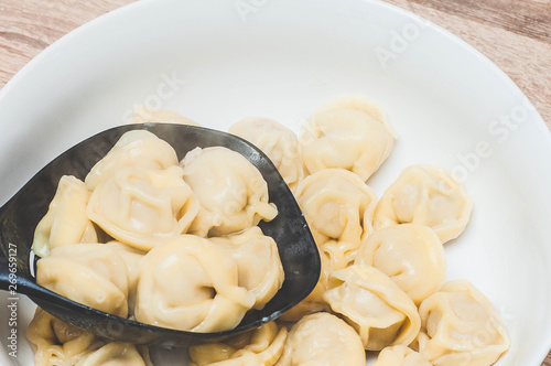 Freshly cooked hot dumplings look appetizing on a white plate in a sieve.