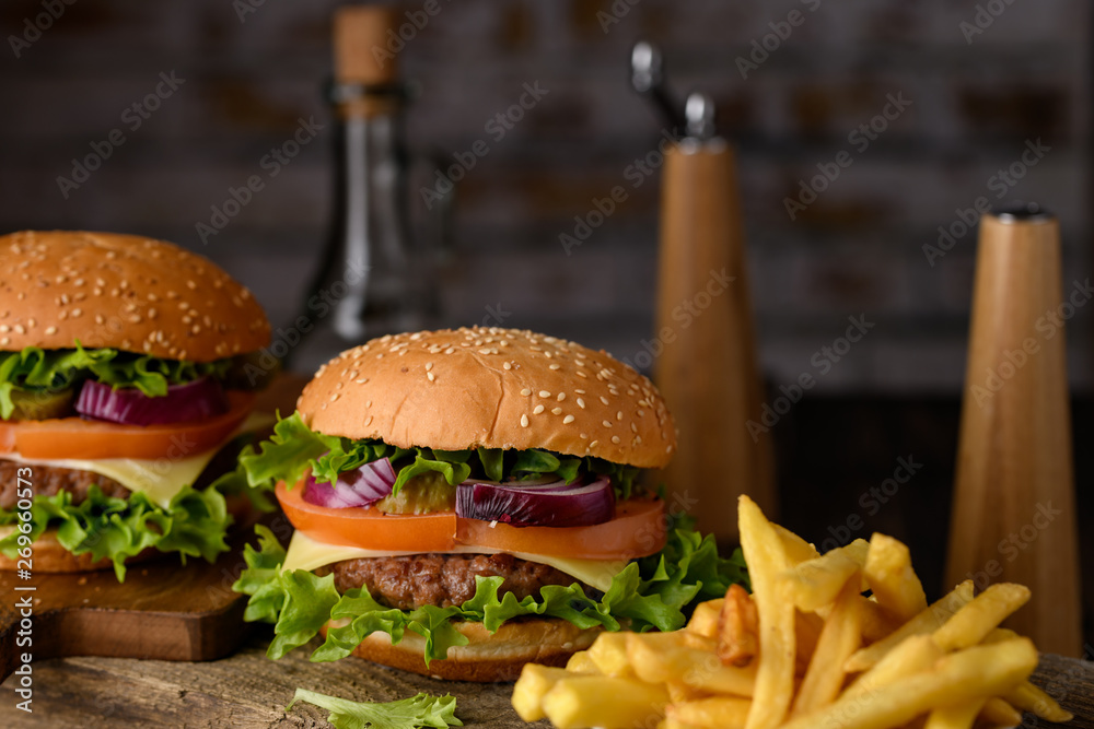 Home cooking burgers and french fries with your hands on a dark wooden background. Home cooking burgers and french fries with your hands on a dark wooden background.