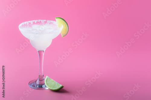 Classic margarita alcohol cocktail with tequila, liqueur, lime juice, sugar syrup, salt and ice, summer pink background, place for text