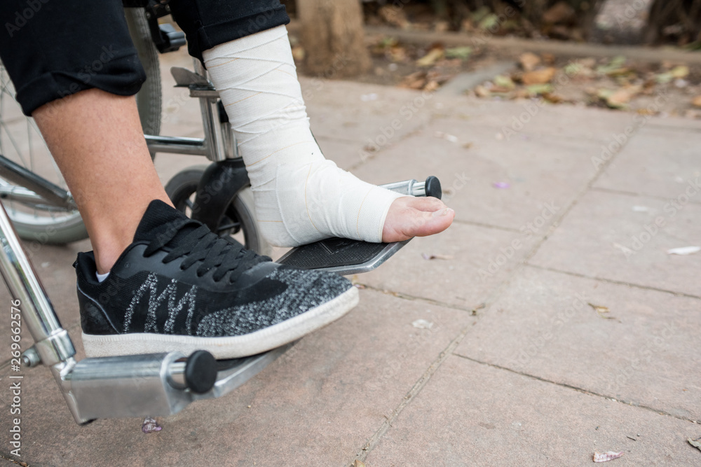 Obraz premium Detail of a foot bandaged in a wheelchair over a brick bottom.