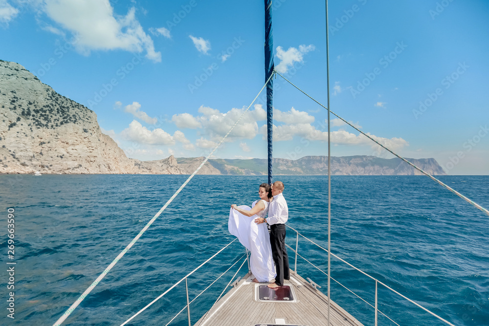 Young Couple Relaxing on a Yacht. Happy wealthy man and a woman by private boat have sea trip.