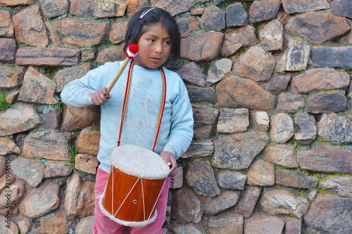 Sad little latin american girl playing typical sikuri drum. photo