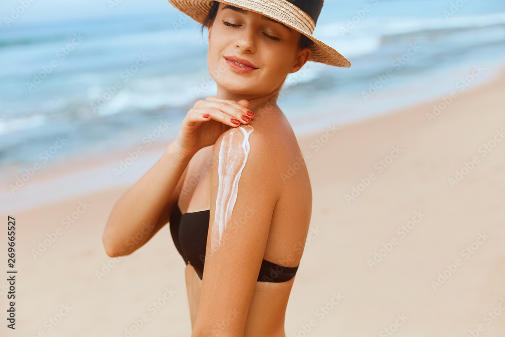 Woman Applying Sun Cream Creme on Tanned  Shoulder . Sun Protection. Skin Care. Girl Using Sunscreen to Skin. Portrait Of Female Holding Suntan Lotion and Moisturizing Sunblock.