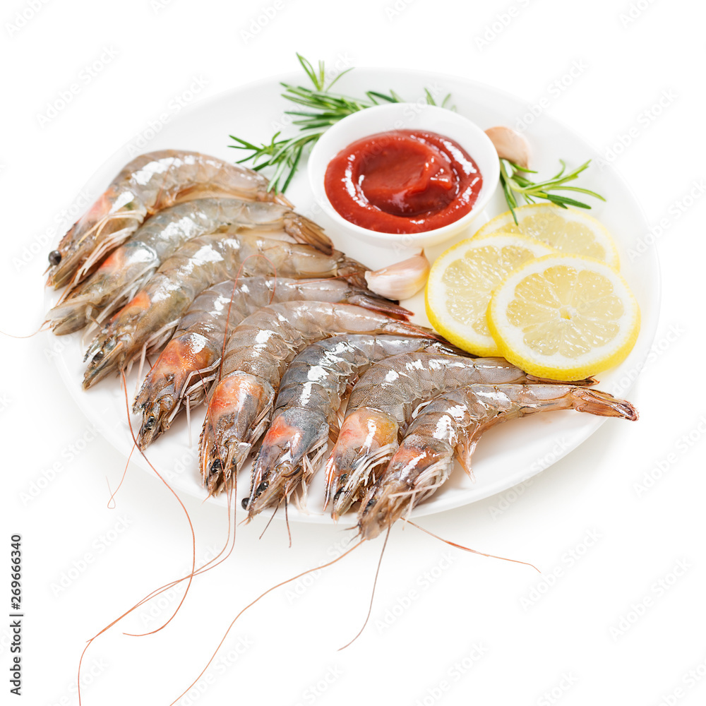 Raw shrimps in white plate with lemon and tomato sauce. isolated on white background Raw shrimps in white plate with lemon and tomato sauce. isolated on white background