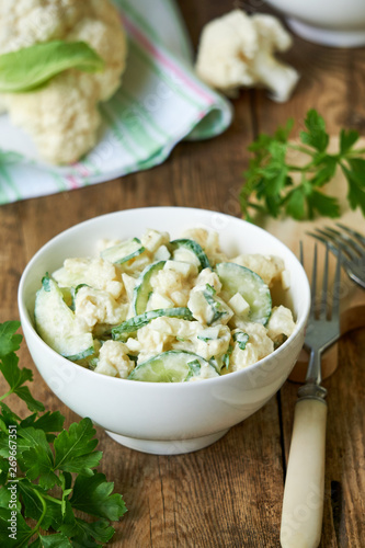 Cauliflower salad with cucumbers and eggs on a wooden background