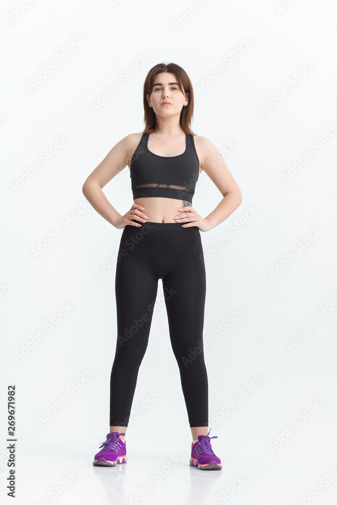 Woman with dark hair in a sportswear stretching in a gym. Exercising for weight loss Woman with dark hair in a sportswear stretching in a gym. Exercising for weight loss