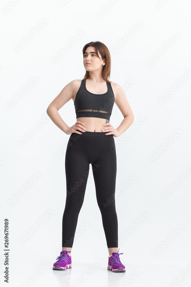 Woman with dark hair in a sportswear stretching in a gym. Exercising for weight loss Woman with dark hair in a sportswear stretching in a gym. Exercising for weight loss