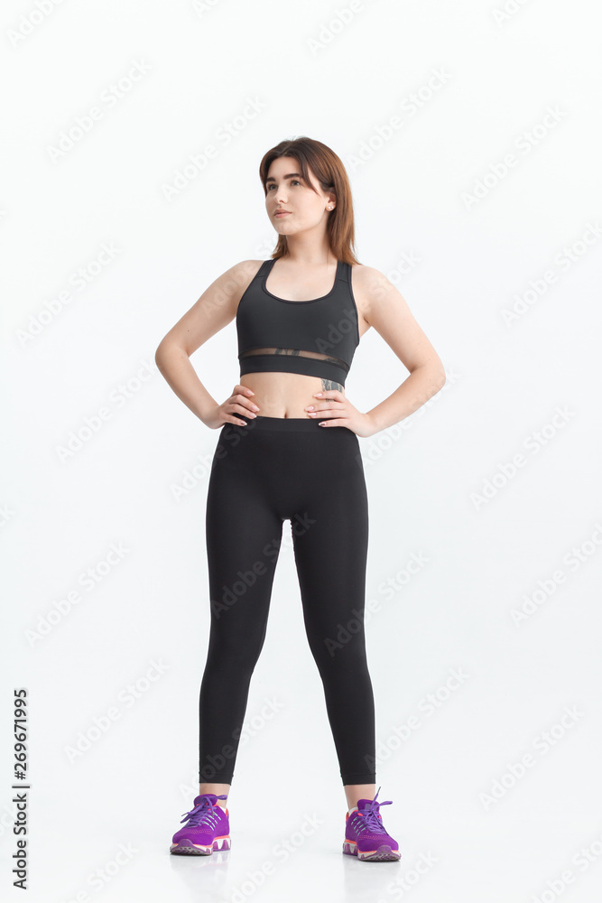 Woman with dark hair in a sportswear stretching in a gym. Exercising for weight loss Woman with dark hair in a sportswear stretching in a gym. Exercising for weight loss
