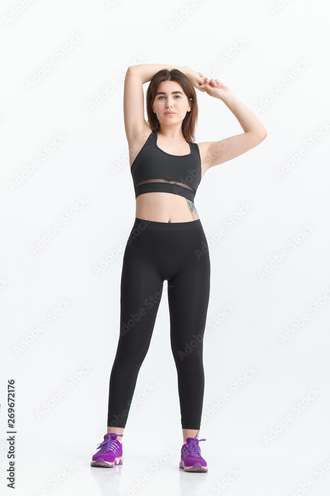 Woman with dark hair in a sportswear stretching in a gym. Exercising for weight loss Woman with dark hair in a sportswear stretching in a gym. Exercising for weight loss