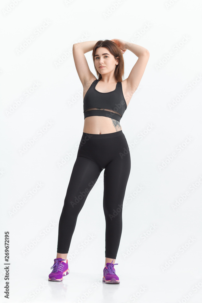 Woman with dark hair in a sportswear stretching in a gym. Exercising for weight loss Woman with dark hair in a sportswear stretching in a gym. Exercising for weight loss