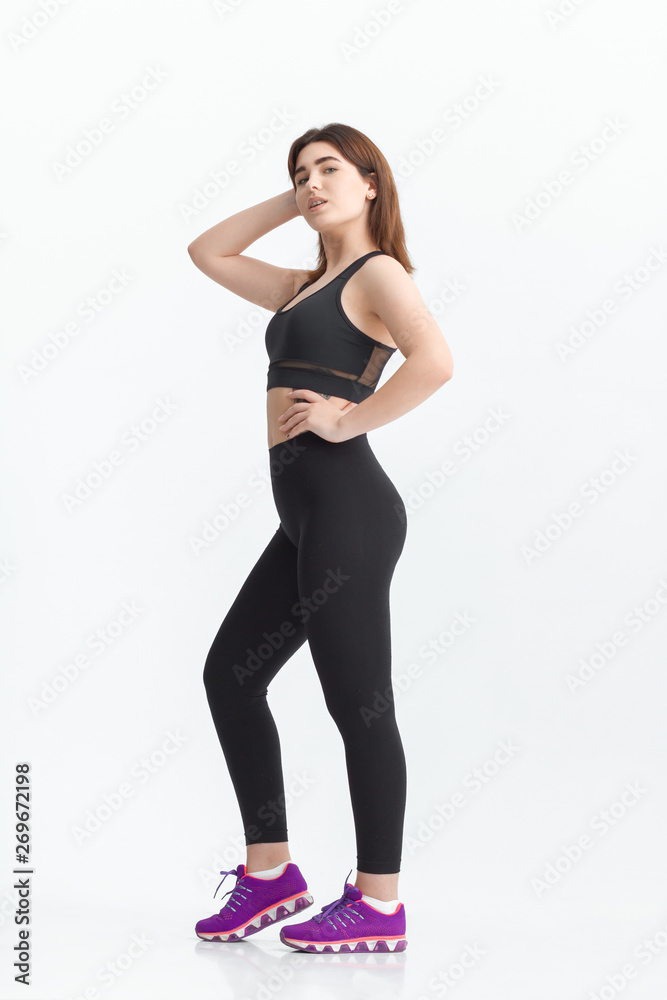 Woman with dark hair in a sportswear stretching in a gym. Exercising for weight loss Woman with dark hair in a sportswear stretching in a gym. Exercising for weight loss