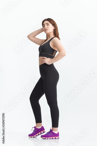 Fototapeta Naklejka Na Ścianę i Meble -  Woman with dark hair in a sportswear stretching in a gym. Exercising for weight loss