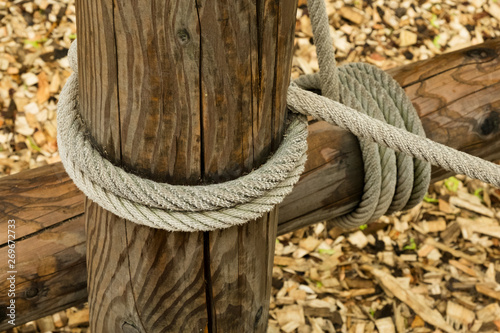 Wooden logs tied with a thick hemp rope. Element of the farm fence. © Aleksey Sidorov