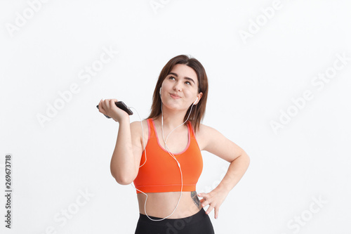 Fototapeta Naklejka Na Ścianę i Meble -  Young brunette woman in a sportswear listening to music during workout.