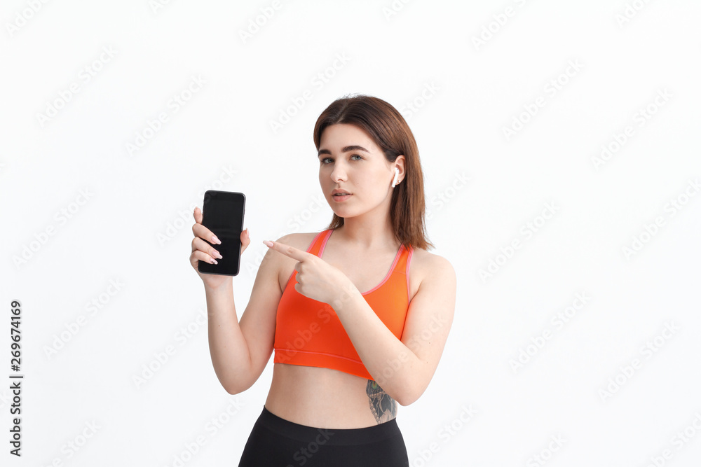 Young fitness woman posing isolated on a white background listening to music with wireless headphones. Young fitness woman posing isolated on a white background listening to music with wireless headphones.