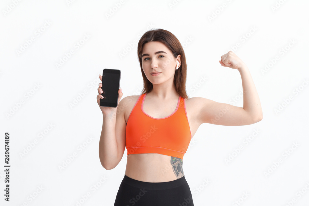 Young fitness woman posing isolated on a white background listening to music with wireless headphones. Young fitness woman posing isolated on a white background listening to music with wireless headphones.