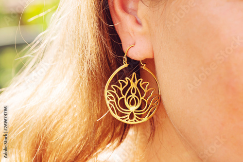 Woman wearing floral lotos shaped earrings closeup