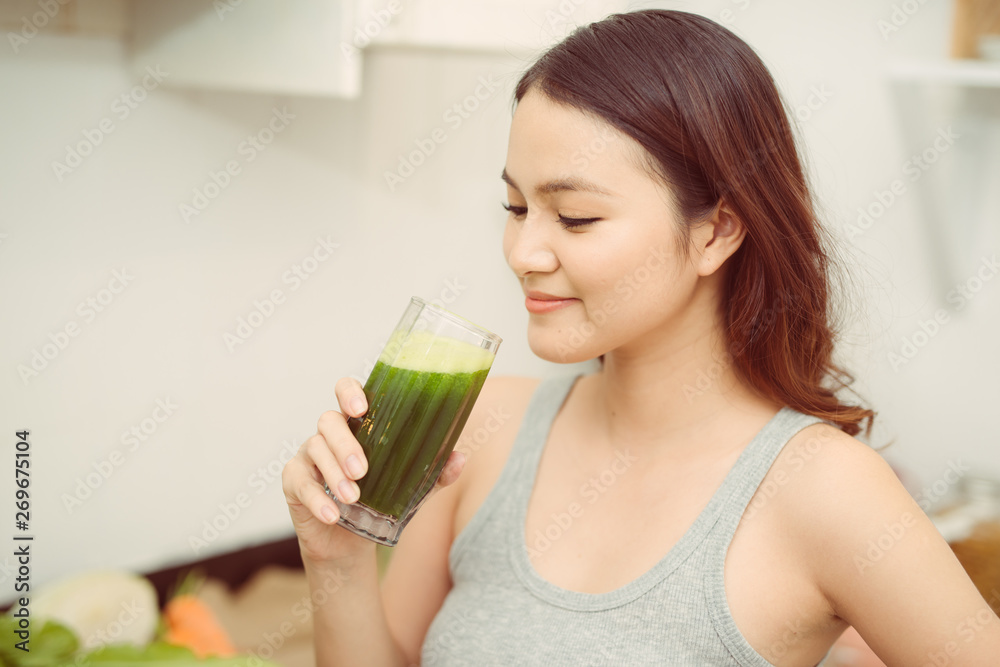 Pretty young woman drinking a vegetable smoothie in her kitchen Pretty young woman drinking a vegetable smoothie in her kitchen