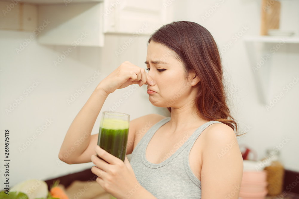 Woman drinking disgusting green smoothie, closing nose, bad smell and taste Woman drinking disgusting green smoothie, closing nose, bad smell and taste