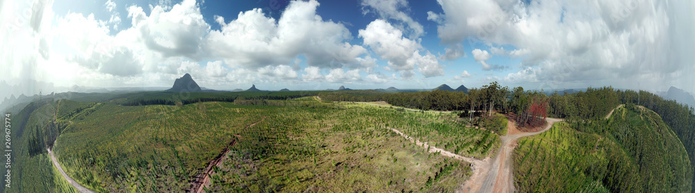Panoramic aerial view of Glass House Mountains National Park on Sunshine Coast (Queensland, Australia). The Glasshouse Mountains are silhouetted in the afternoon sunlight.