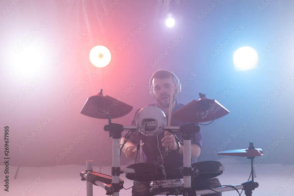 Music, hobby and people concept - young man drummer playing the electronic drums on the stage