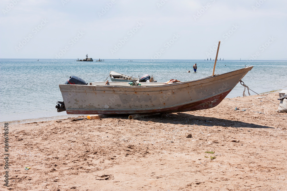 Old fishing boat with motor on the coast and in the sea water in summer. Old fishing boat with motor on the coast and in the sea water in summer.