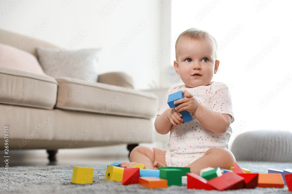 Cute baby girl playing with building blocks in room. Space for text Cute baby girl playing with building blocks in room. Space for text