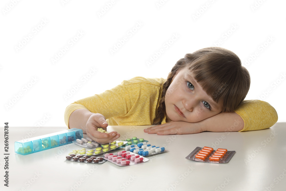 Little child with many different pills on white background. Danger of medicament intoxication Little child with many different pills on white background. Danger of medicament intoxication