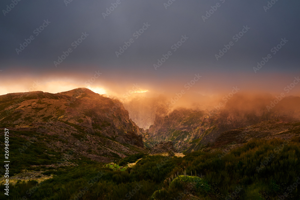Obraz premium Mountain at sunset with gold clouds and dramatic light in Madeira,pico de arieiro