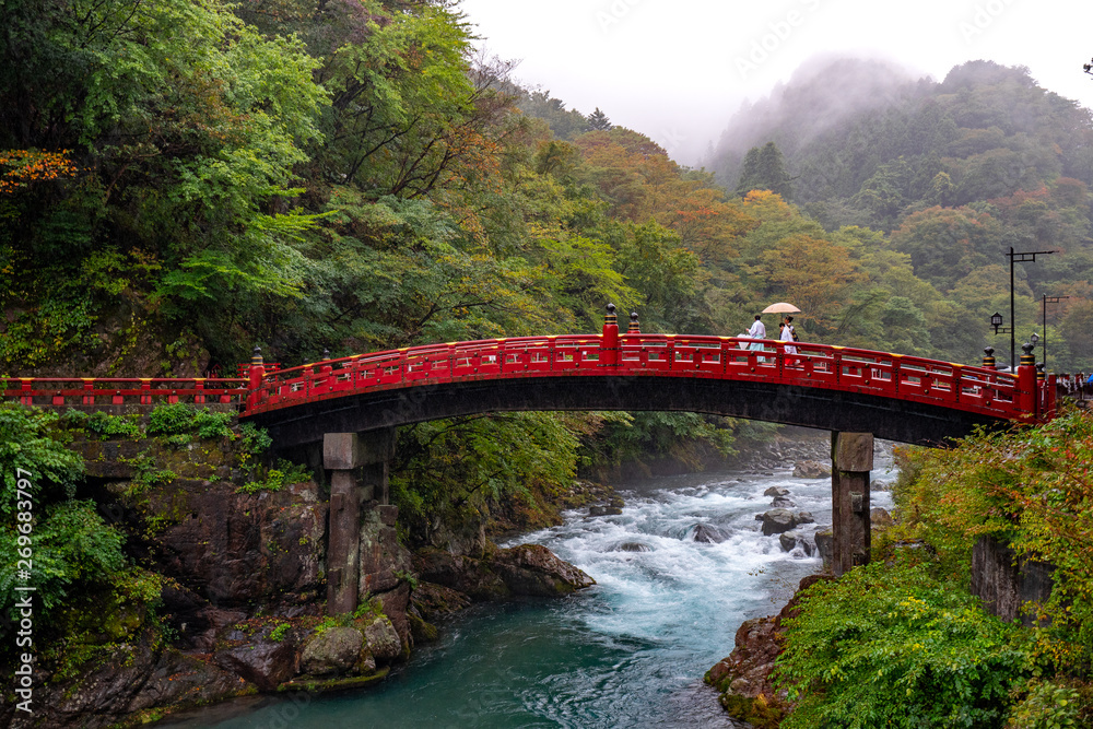 people walking aceoss a bridge over the river in nikko japan people walking aceoss a bridge over the river in nikko japan