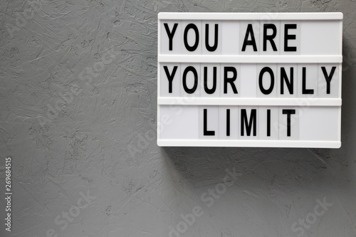 'You are your only limit' words on a modern board over gray background, overhead view. Top view, from above. Flat lay. Copy space.