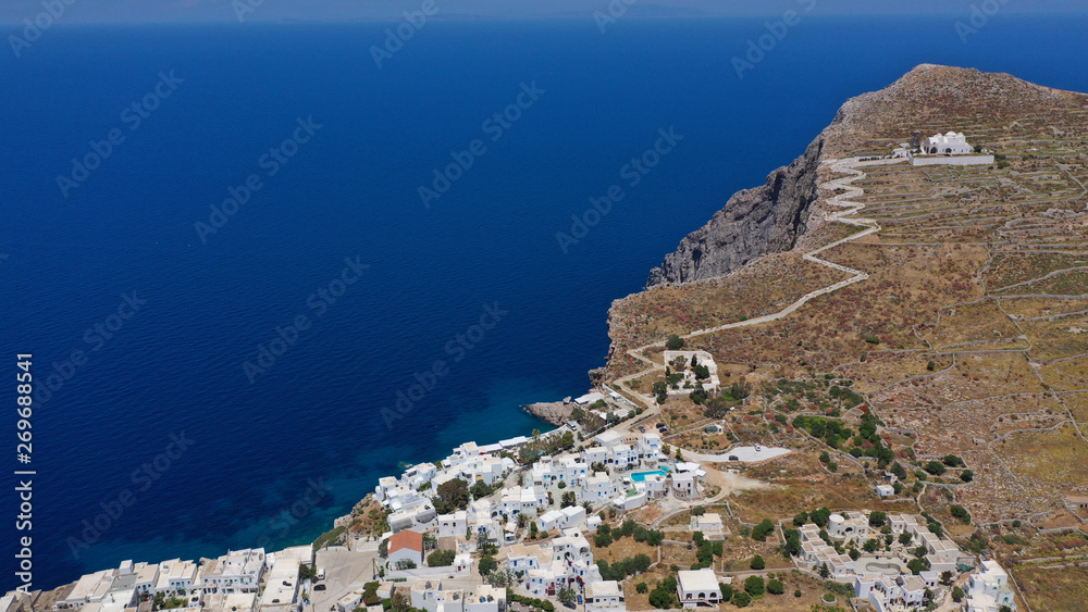 Naklejka premium Aerial drone photo of iconic and picturesque main village (chora) of Folegandros island featuring castle and built on top of steep hill overlooking the Aegean blue sea, Cyclades, Greece
