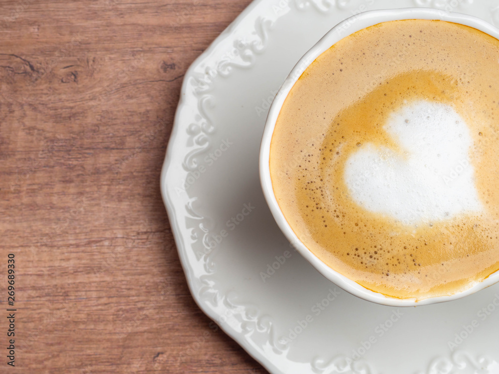 Close up white coffee cup with heart shape latte art on wood table at cafe. Close up white coffee cup with heart shape latte art on wood table at cafe.
