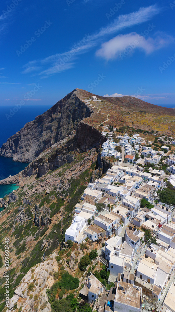 Aerial drone photo of iconic and picturesque main village (chora) of Folegandros island featuring castle and built on top of steep hill overlooking the Aegean blue sea, Cyclades, Greece