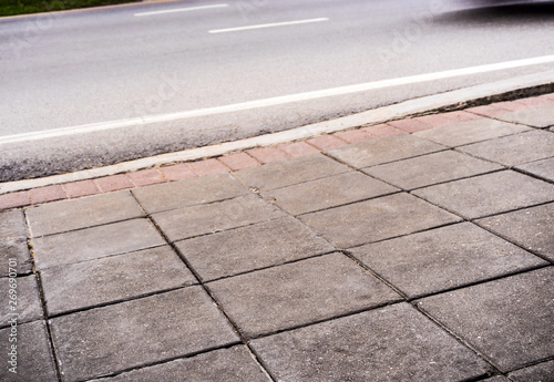 The road side pathway is paved with square blocks of concrete